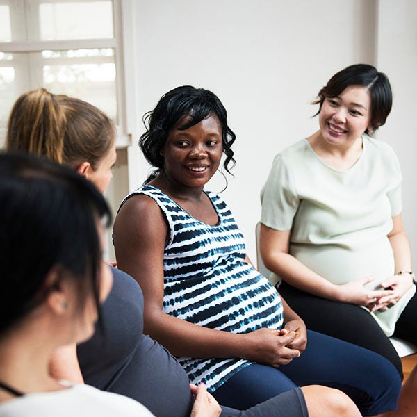 Pregnant women smiling at each other