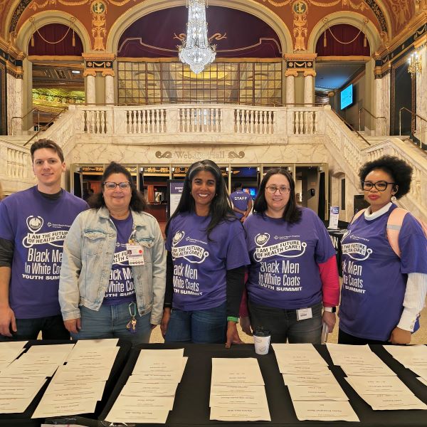 Black Men In White Coats volunteers' welcome guests during registration.