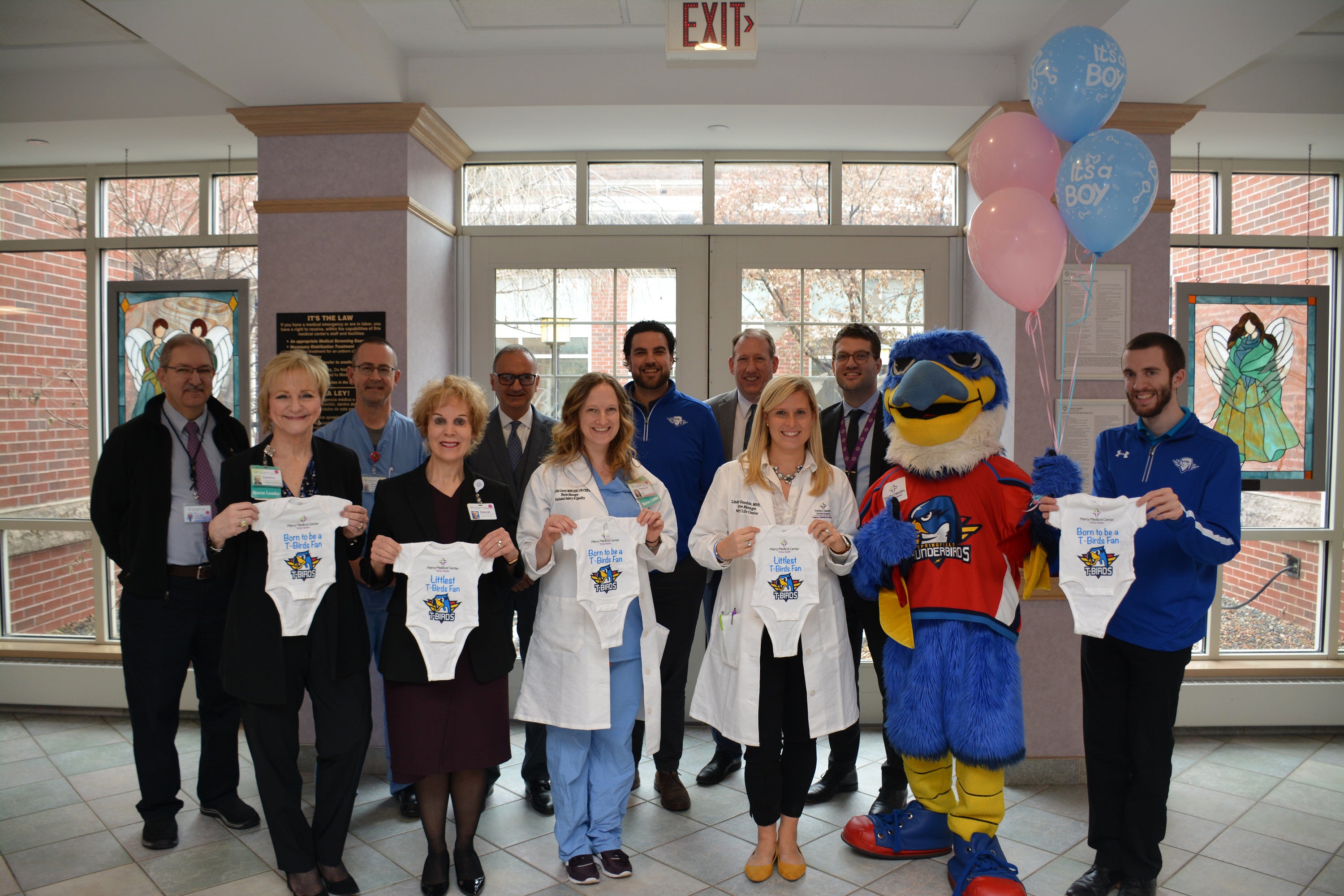 Mercy Life Center Employees and Springfield Thunderbirds holding up onsies with balloons and smiling